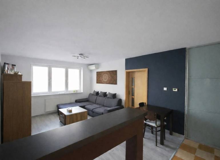 Nappali egy háromszobás lakásban sarokkanapéval és fa dekorációjú padlóval.