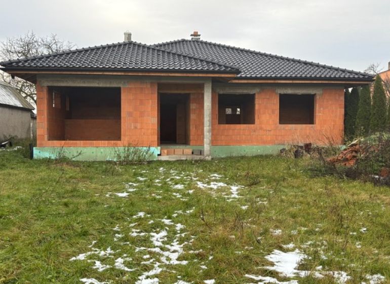 Befejezetlen családi ház Dúbravkában, fekete tetővel és üres ablakokkal, a téli kertben.
