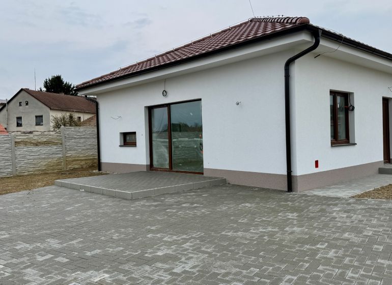 Családi ház a Fő utcán, Vágfarkasdon fehér homlokzattal és kövezett udvarral.