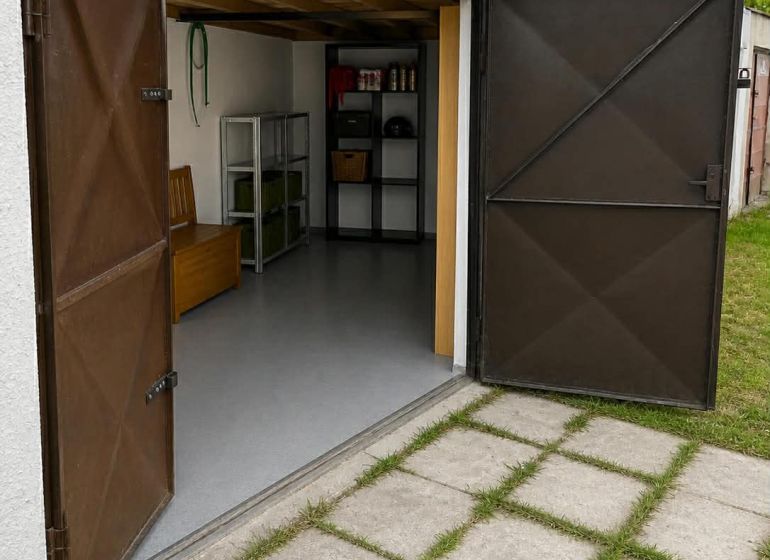 Nyitott garázsok Érsekújváron polcokkal és beton járdával.
