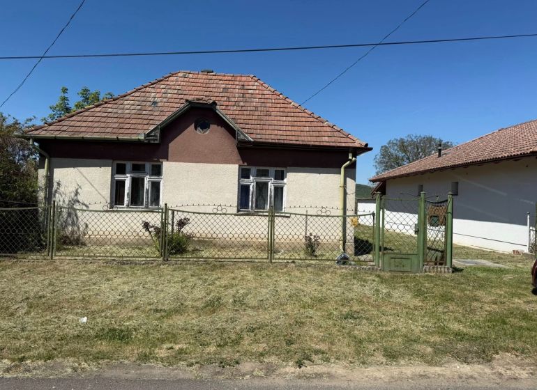 A Honti családi háznak ferde teteje van és fém kerítéssel van körbekerítve.