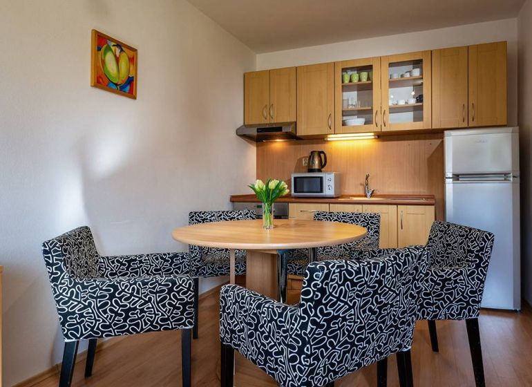 Konyhasarok étkezőasztallal és székekkel a nyaraló apartmanban, fa dekorációjú padlóval.