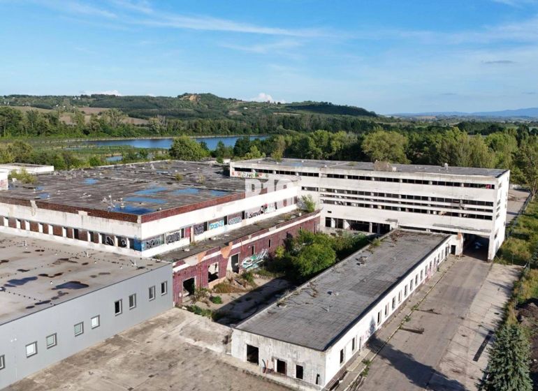 Gyártóhelyiségek Lévában elhagyatott épületekkel, amelyeket természet és vízfelület vesz körül.