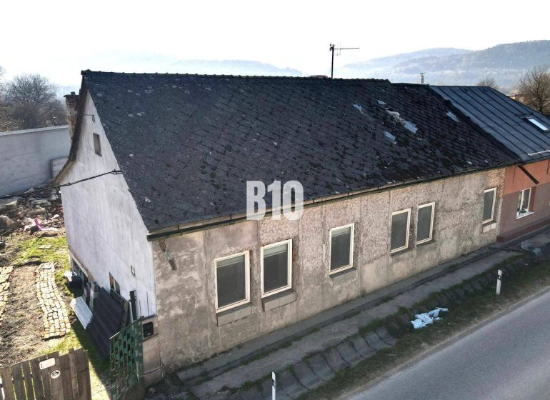 Családi ház Nagybiccseben kopott tetővel és vakolattal, főút mellett.