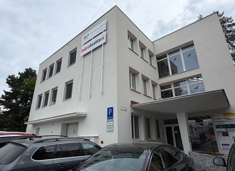 Irodaház a Prievidza Dlhá utcáján parkoló autókkal.