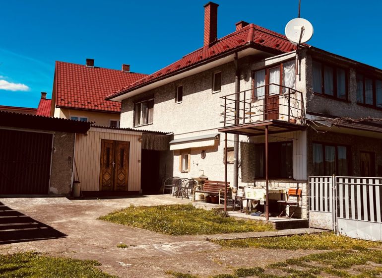Családi ház Újkelcsén, Újkelcse udvarral, garázzsal és erkéllyel a kék ég alatt.