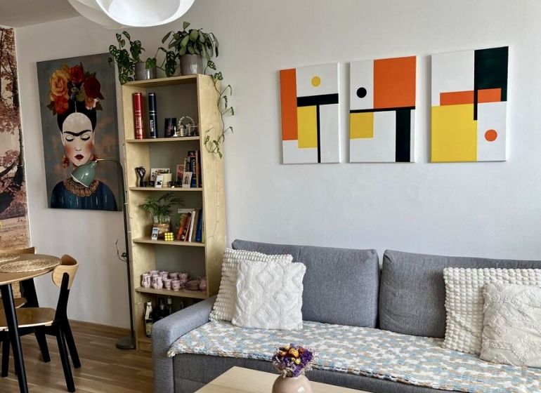 Nappali egy kétszobás lakásban kanapéval, asztallal és fa dekorációjú padlóval.