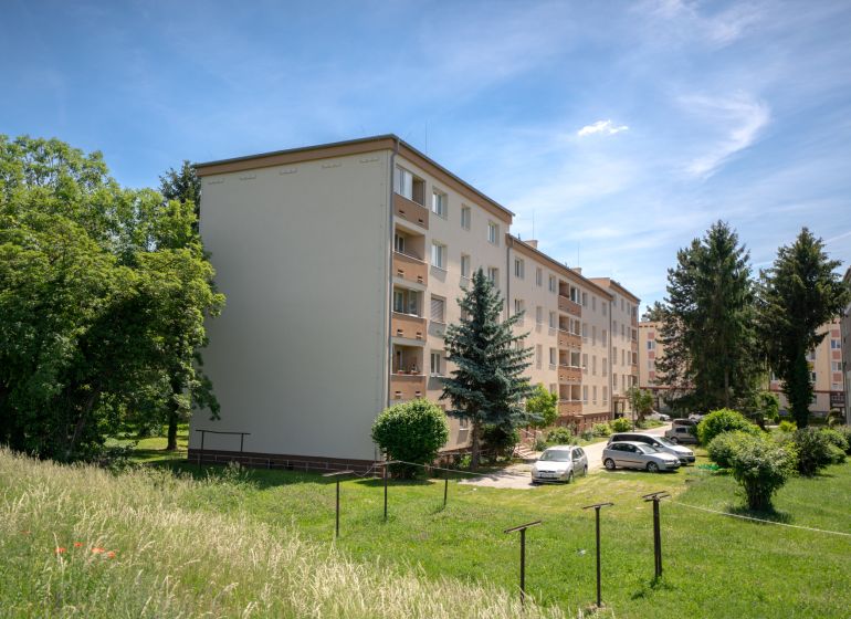 A Švermova utcai lakóházak Trencsénben a környező zöldterülettel és parkoló autókkal.