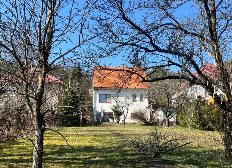 Családi ház Podhájban, Kráľovában, fákkal és gyepes területtel körülvéve, narancssárga tetővel.