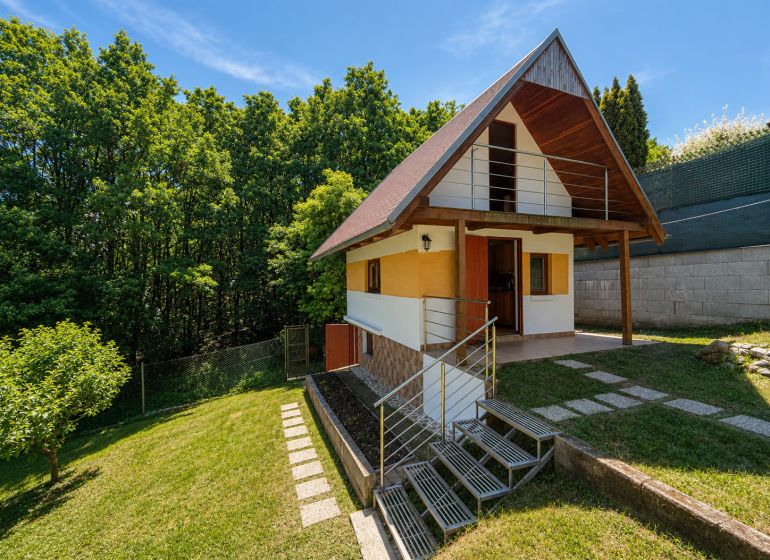 Faház fa dekorációval Považská Bystricában, Klučina területén, zölddel és fákkal körülvéve.