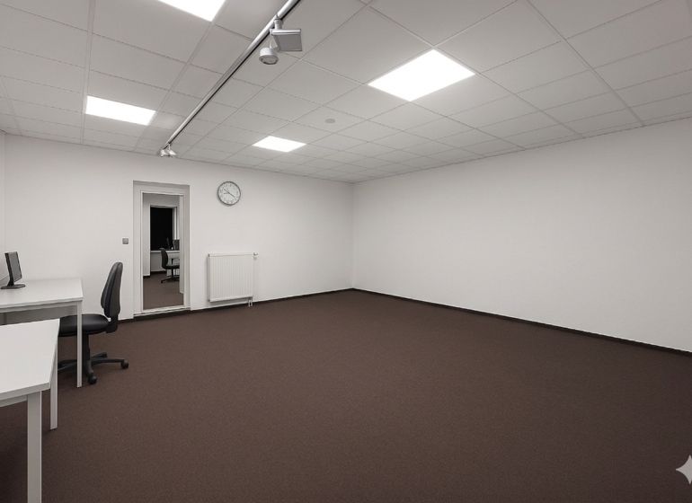 Priestranné Kancelárie s bielymi stenami, hnedým kobercom a minimalistickým zariadením.