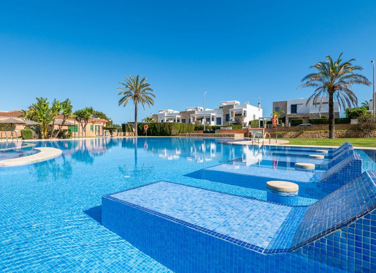 Medence a Cala Murada-i nyaraló apartman mellett Mallorcán, pálmafákkal és napozóágyakkal.