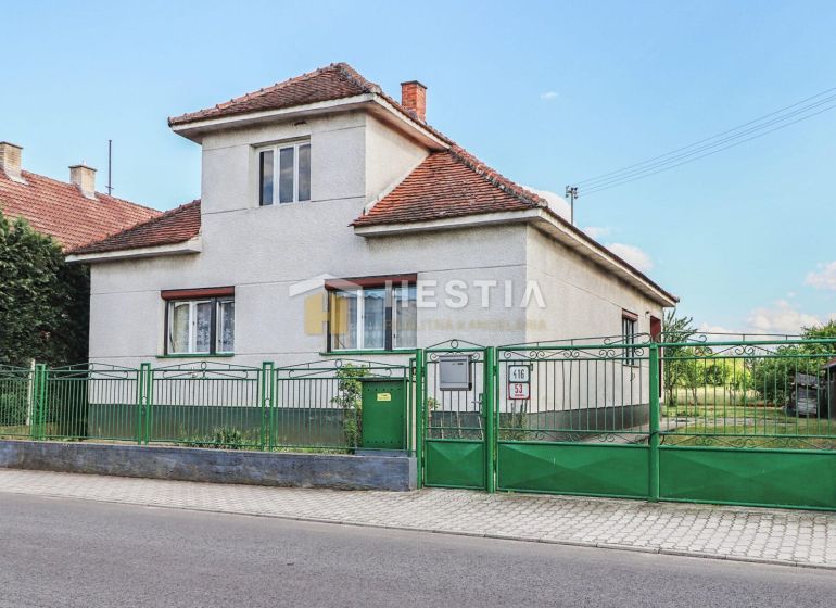 Családi ház Borsky Mikulášban fehér falakkal és zöld kerítéssel.
