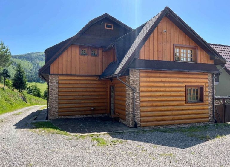 Családi ház Nagyborovón, fával és kővel burkolt külsővel, az erdő mellett.