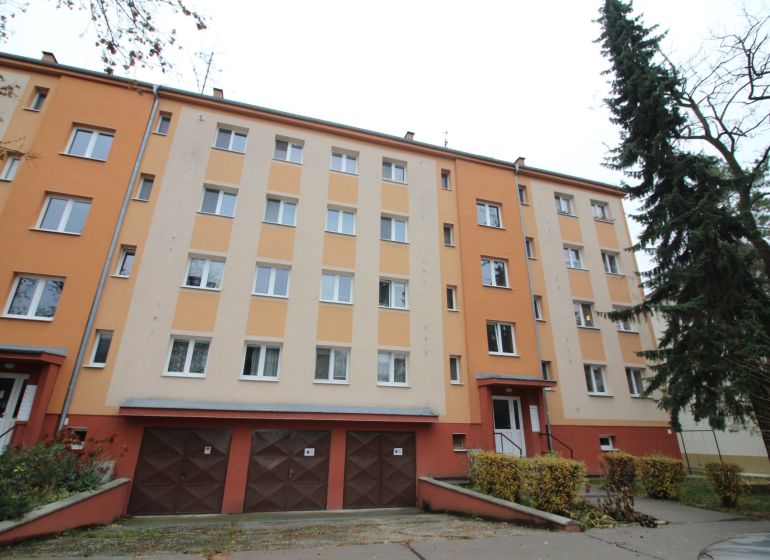 Tömbház Trnavában színes homlokzattal, garázsokkal és fákkal körülvett környezettel.