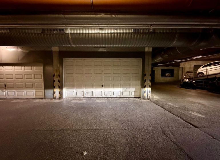 A garázs belseje zárt kapukkal és parkoló járművekkel.