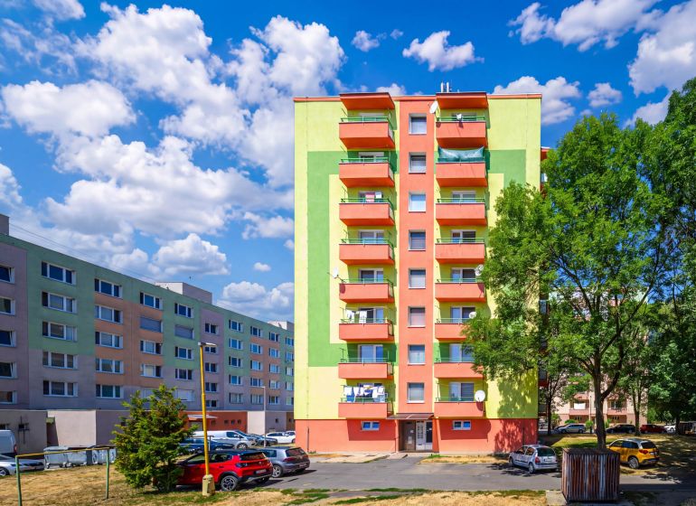 Színes lakóházak a Füleki Sládkovič utcában parkolóval és zöldterülettel.