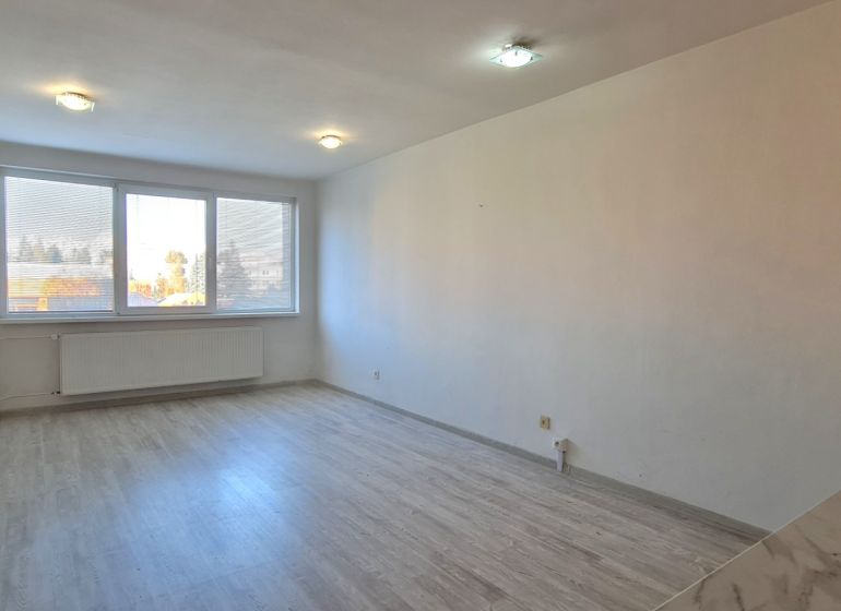 Világos szoba fa dekor padlóval egy kétszobás lakásban, nagy ablakkal.
