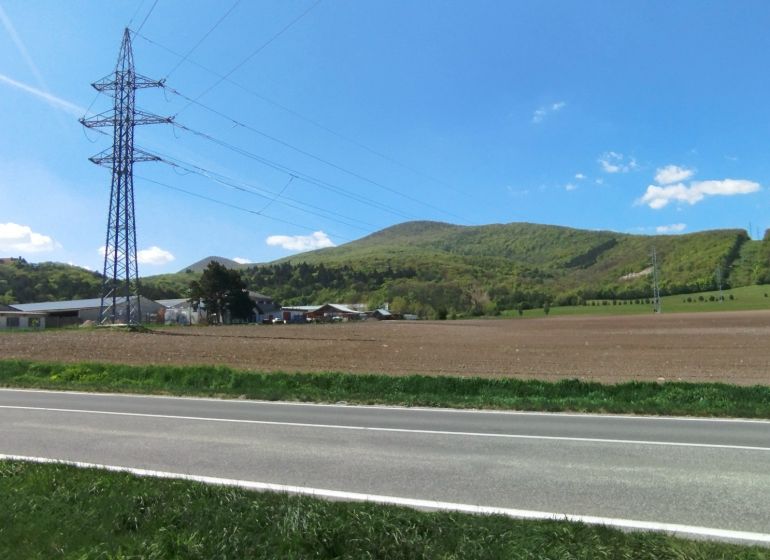 Táj a Smolenice-i Továrenská utcában mezőgazdasági és erdőterületekkel, valamint elektromos vezetékkel.