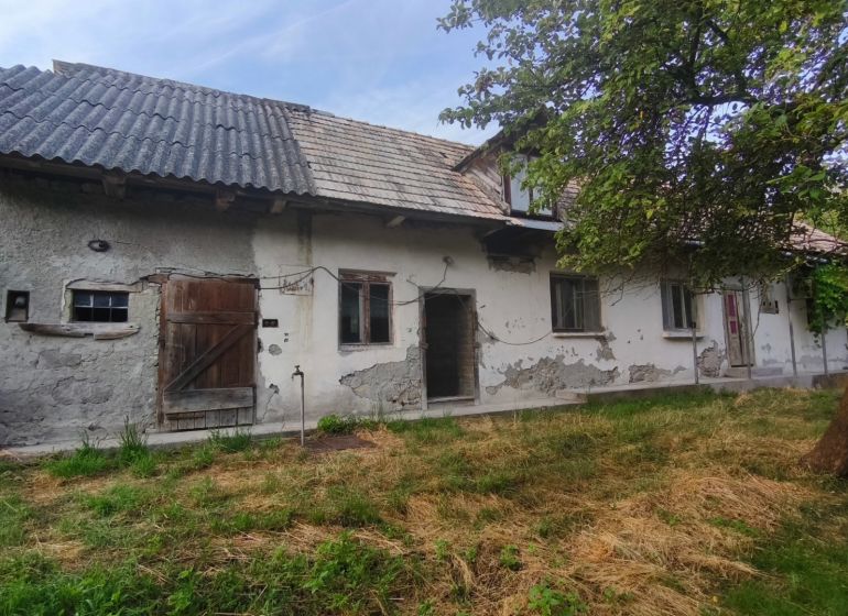 Családi ház Csélócban kopott vakolattal, faajtókkal és kerttel.