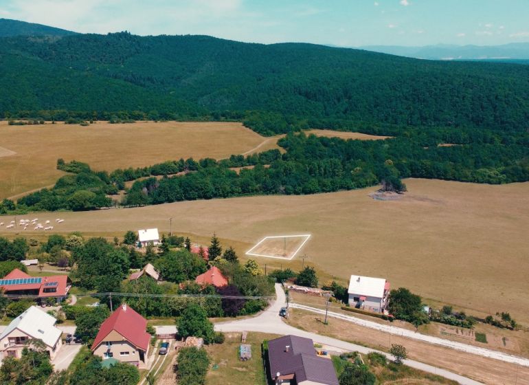 Vidékies kilátás a Podhradí lakóterületeire, amelyeket erdők és rétek vesznek körül.