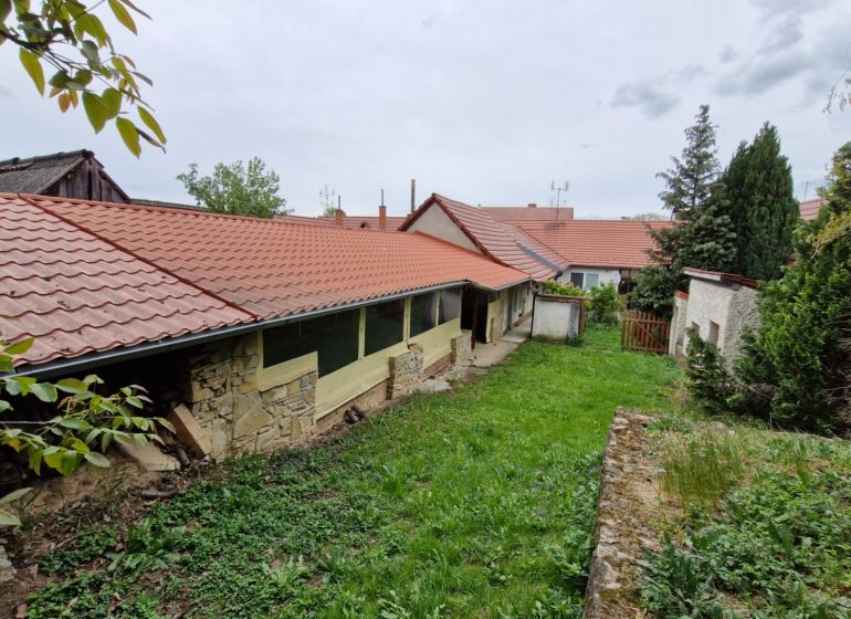Kert a családi ház mellett Mokrý Hájban, kőfallal és piros tetőfedéssel.