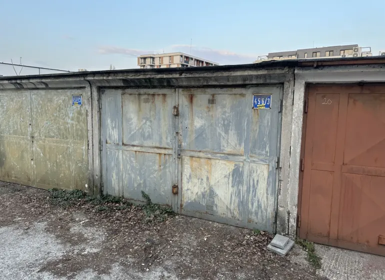 Elhagyatott garázsok Pozsony-Újvárosban, lehullott vakolattal és bádogajtókkal.
