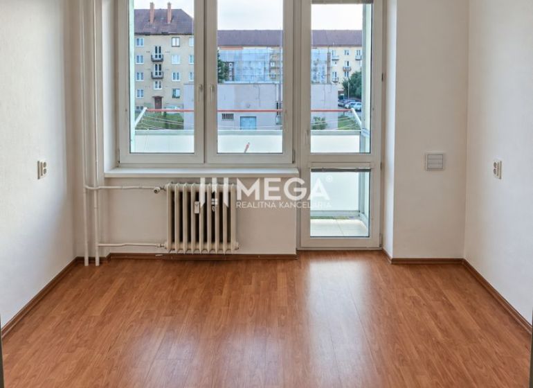 Szoba egy kétszobás lakásban, fa dekorációjú padlóval és nagy ablakkal.