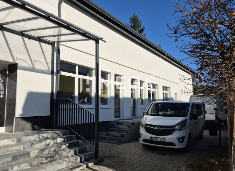 Épület üzlethelyiségekkel a humennéi Tyršova utcán, parkoló autók, fa.