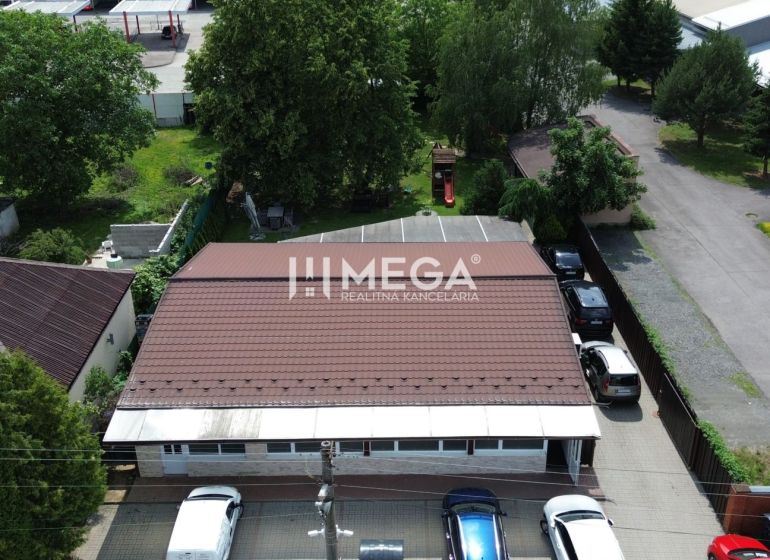 Vendéglátóhelyiségek a Budovateľská utcában, Vranov nad Topľou városában, autókkal és zölddel körülvéve.