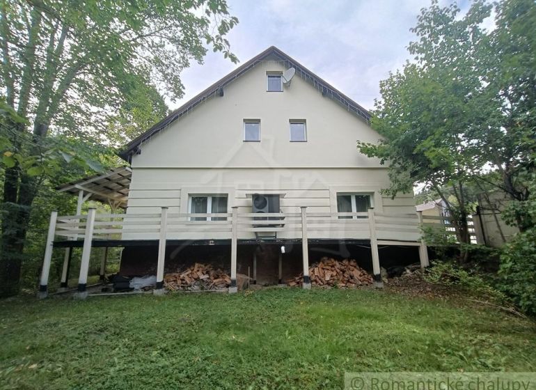 Családi ház Staškovóban, zölddel körülvéve, a terasz alatt tárolt fával.
