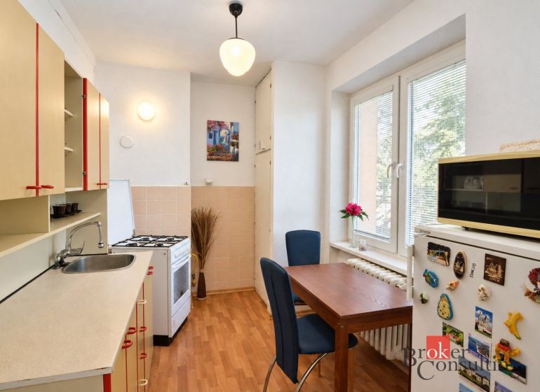 Konyha egy kétszobás lakásban fa dekor padlóval, étkezőasztallal és modern felszereléssel.