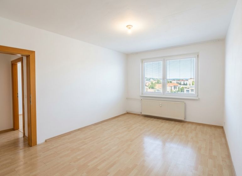 Szoba egy háromszobás lakásban nagy ablakkal és fa dekorációjú padlóval.