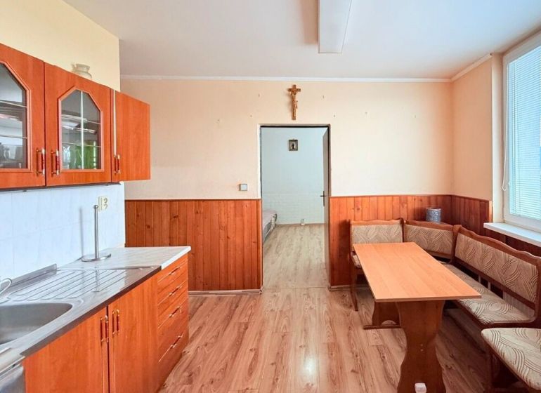 Konyha egy háromszobás lakásban konyhabútorral és étkezőasztallal.