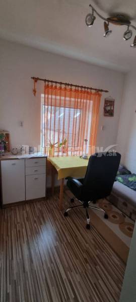 Izba s kreslom, stolom a skrinkou, vhodná pre rodinný dom na ulici Chrenovec.