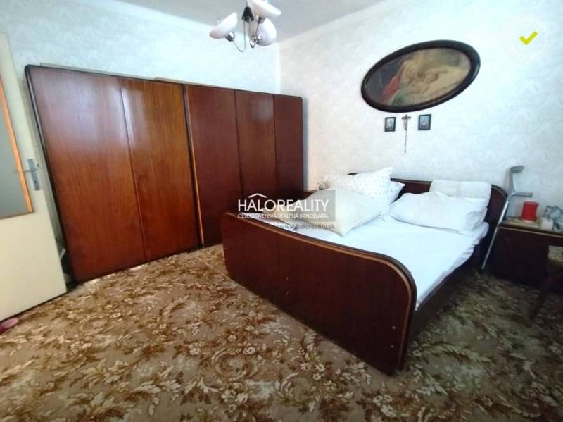 Spálňa v rodinnom dome s drevenými skriňami a posteľou, koberec, nástenné dekorácie.