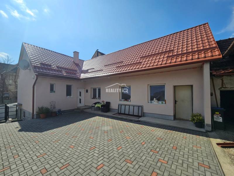 Rodinný dom s červenou strechou a spevneným dvorom ponúka pohodlné bývanie.