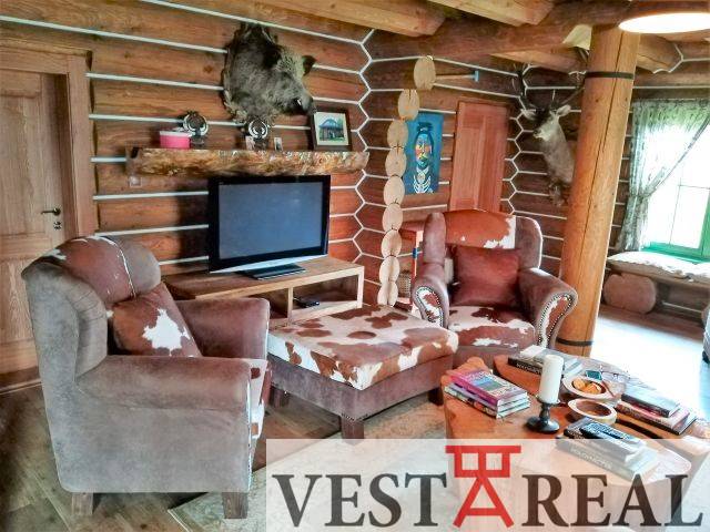 Rustikálna obývacia miestnosť v chate: drevo, kožušiny, TV, kreslá, krb, dekorácie.