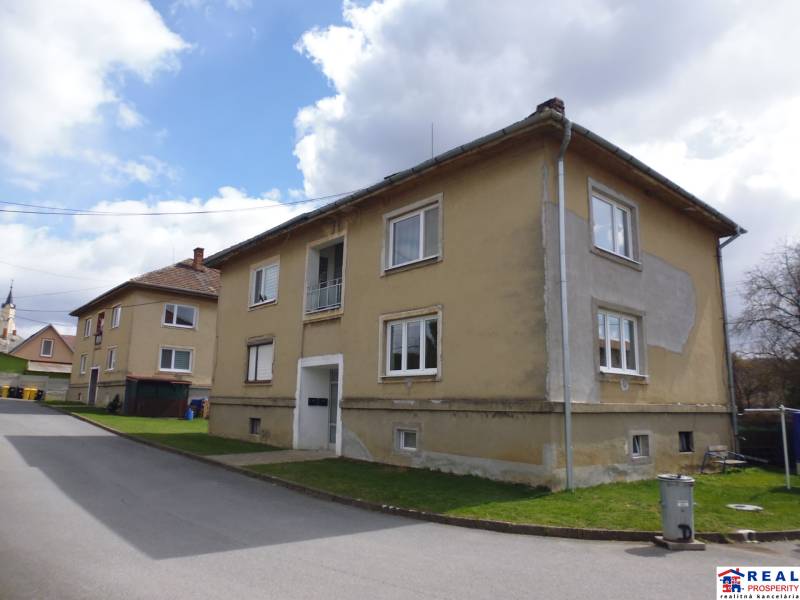 Na obrázku je starší obytný dom s upraveným exteriérom na tichej ulici.