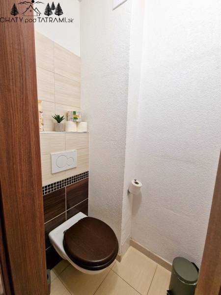 Na ulici Trangoška, Rekreačný apartmán: WC, dlaždice, drevené sedadlo, úložný priestor, osvetlené prostredie.