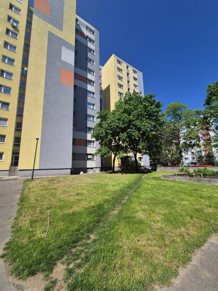 Výškový bytový dom s farebnou fasádou, trávnatou plochou a zeleňou v Dúbravke na Repašského.