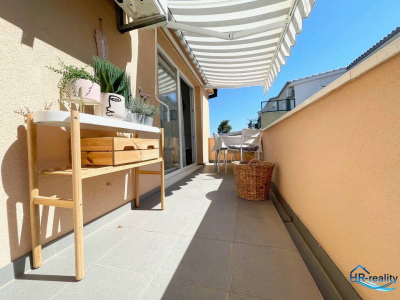 A Šolta-i nyaraló apartman terasza bútorokkal, dekoratív növényekkel és napellenzővel.