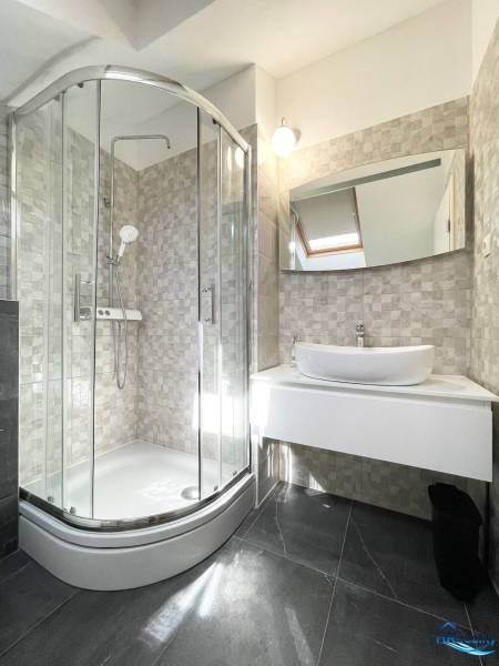 Fürdőszoba egy üdülő apartmanban modern zuhanyzóval és mosdóval.
