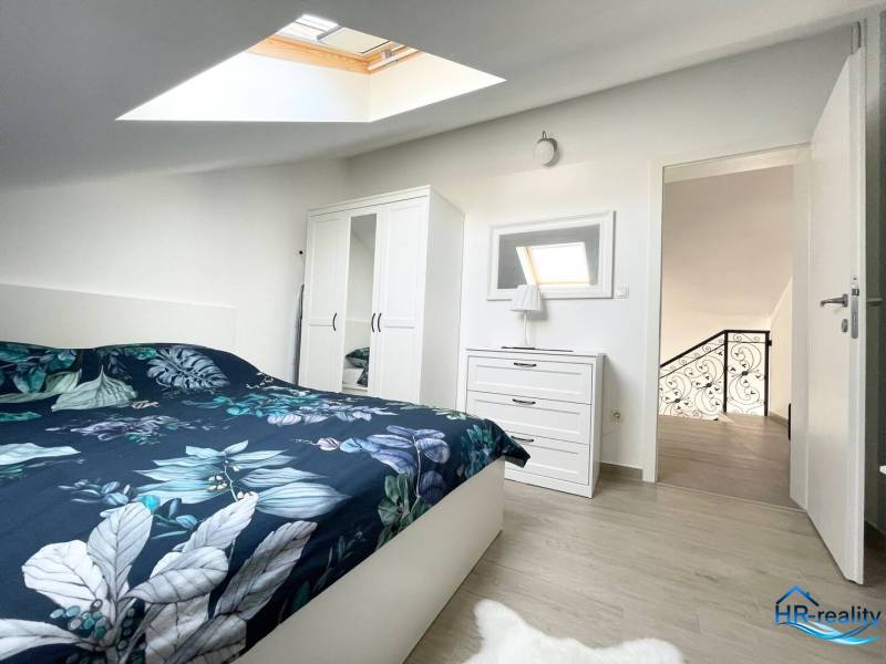 Hálószoba egy üdülő apartmanban ággyal, szekrénnyel és tetőablakkal.