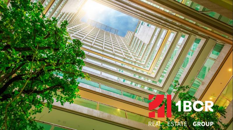 Kilátás az átriumból a lakásépítésre, a 1BCR Real Estate Group logójával.