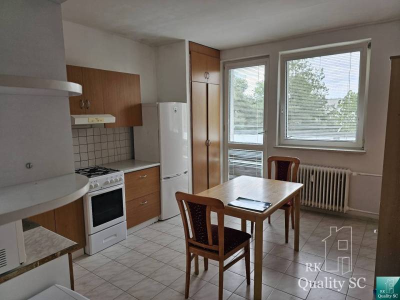 Konyha egy kétszobás lakásban konyhabútorral, asztallal és székekkel.