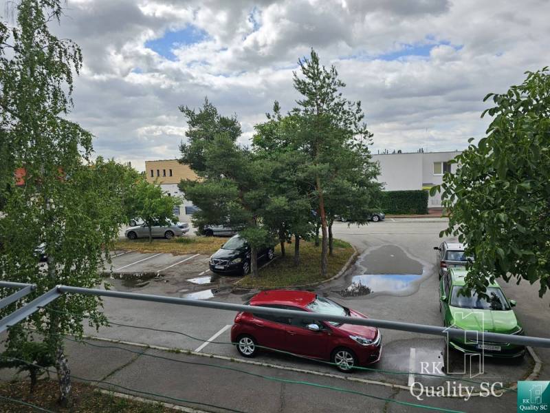 Parkoló a Szenci Zsitva utcában autókkal és fákkal.