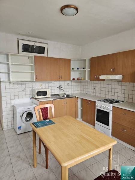 Konyha egy kétszobás lakásban konyhabútorral, étkezőasztallal és háztartási gépekkel.