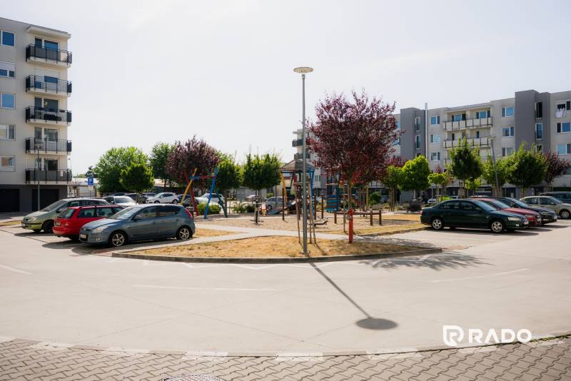 Parkoló és modern lakóházak Trencsénben játszótérrel.