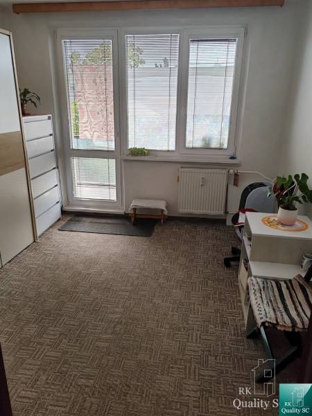 Egy szoba egy háromszobás lakásban szőnyeggel, bútorokkal és nagy ablakokkal, kilátással.